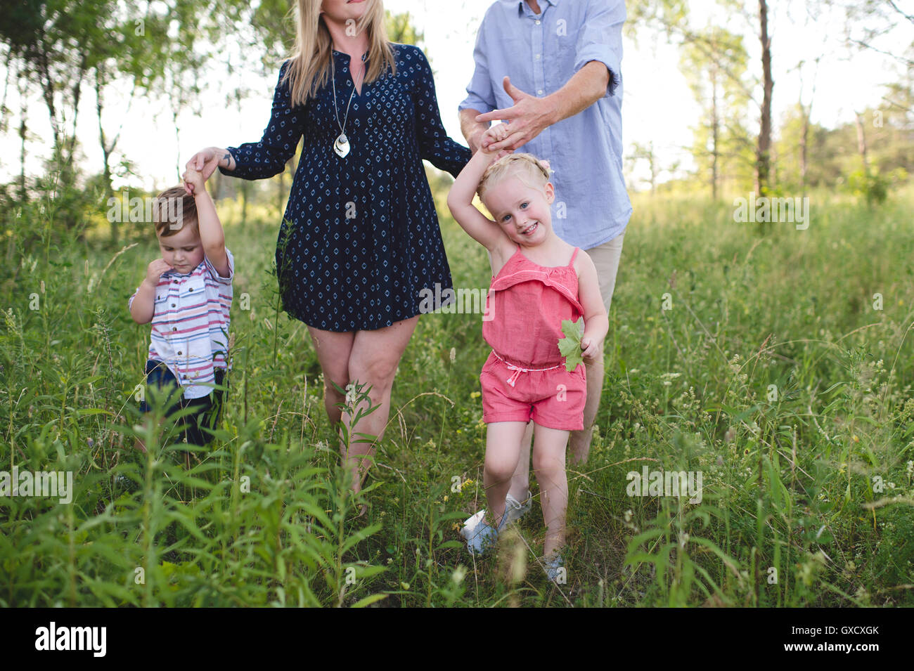 Mid adult parents strolling in meadow boy and girl Stock Photo