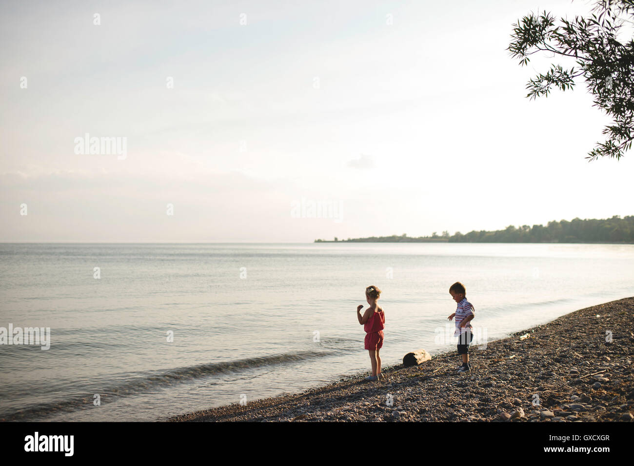 Girl and brother throwing pebbles into Lake Ontario, Oshawa, Canada Stock Photo