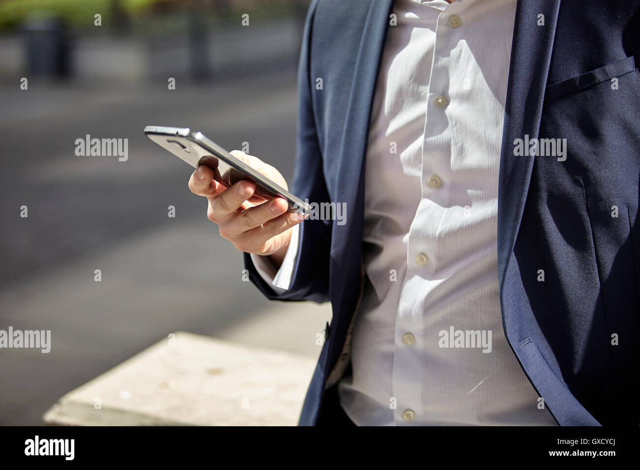 Mid section of businessman texting on smartphone in city Stock Photo ...