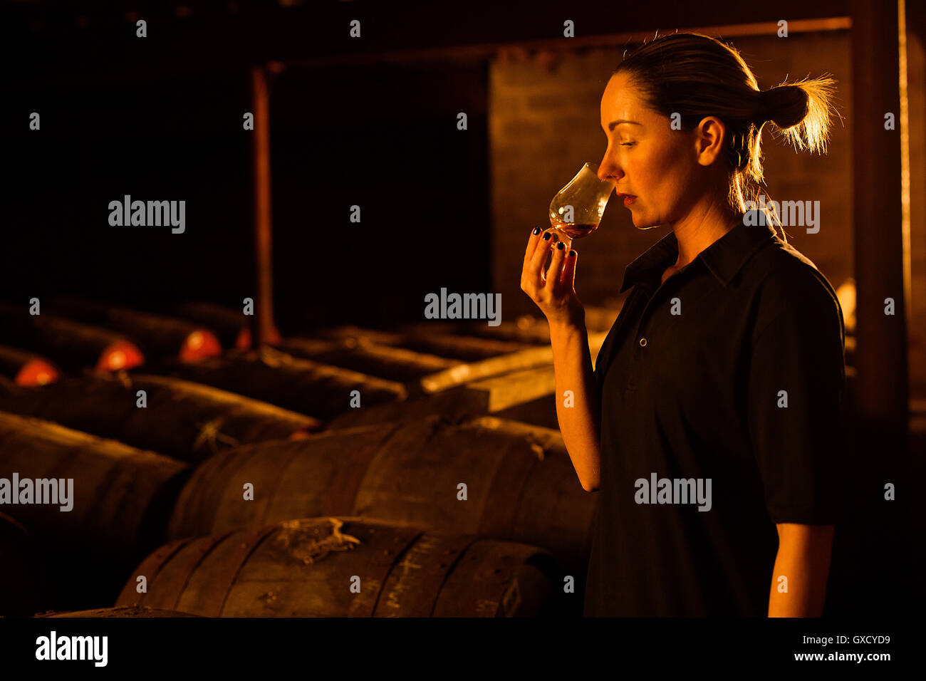 Female taster smelling whisky in glass at whisky distillery Stock Photo