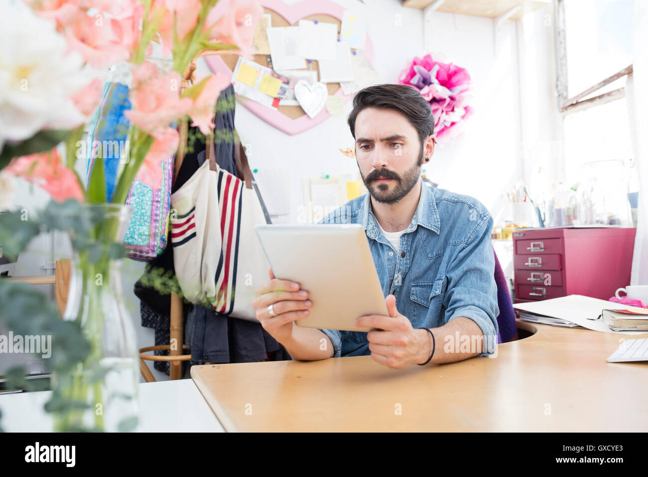 Young male designer reading digital tablet in printing press studio