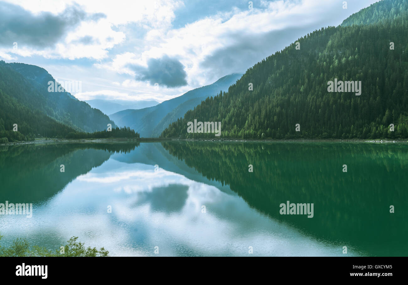 Pine trees and clouds reflected in mountain lake, Sufers, Canton Graubunden, Switzerland Stock Photo