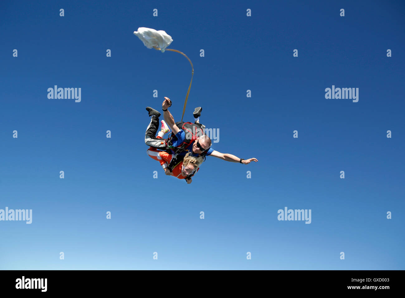 Tandem sky divers free falling with parachute opening, Interlaken, Berne, Switzerland Stock Photo