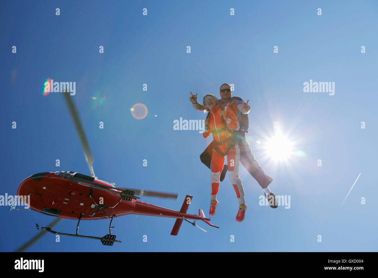 Tandem sky divers free falling with helicopter above, Interlaken, Berne, Switzerland Stock Photo