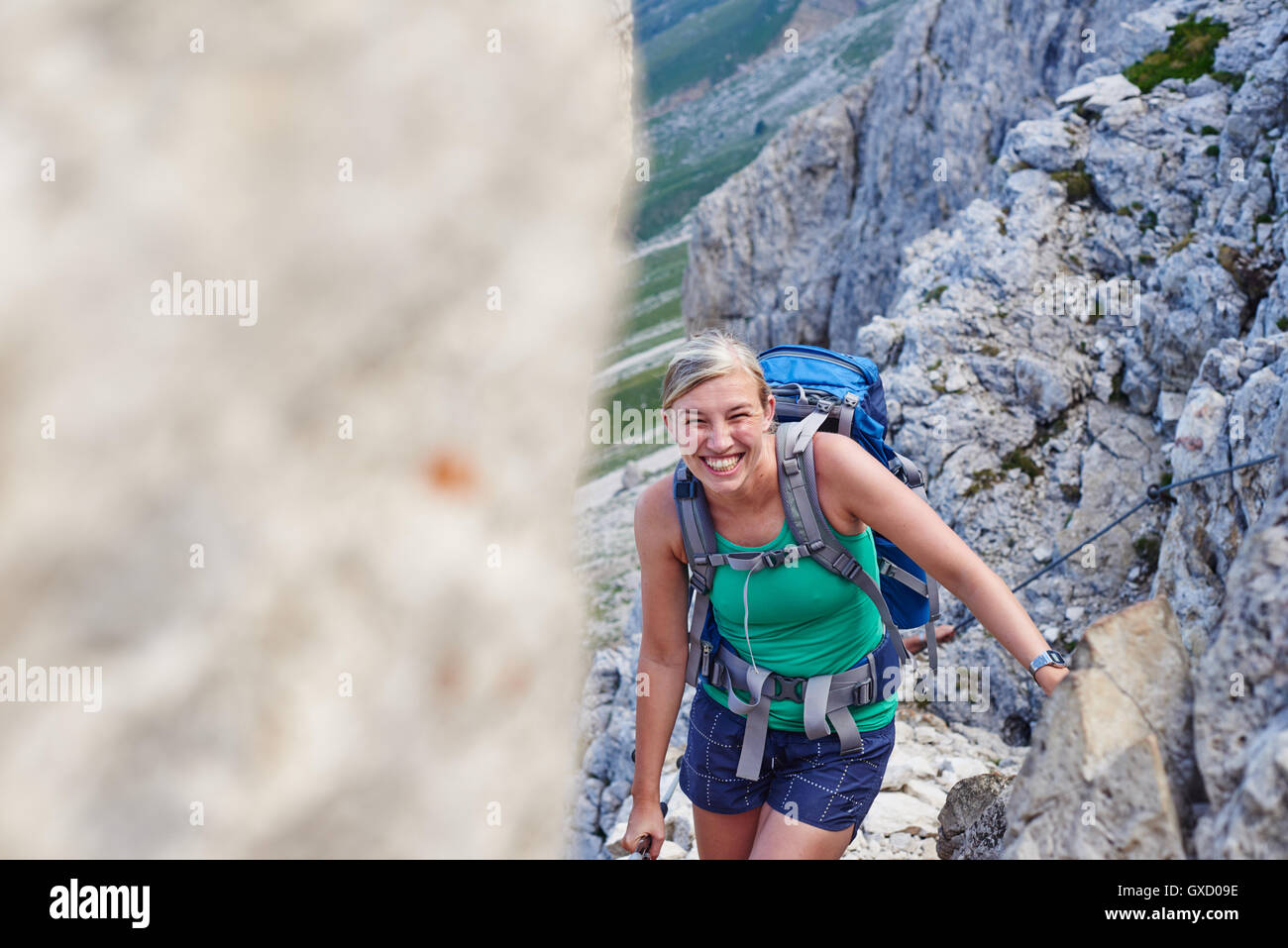 Woman hiking up mountain looking at camera smiling, Austria Stock Photo