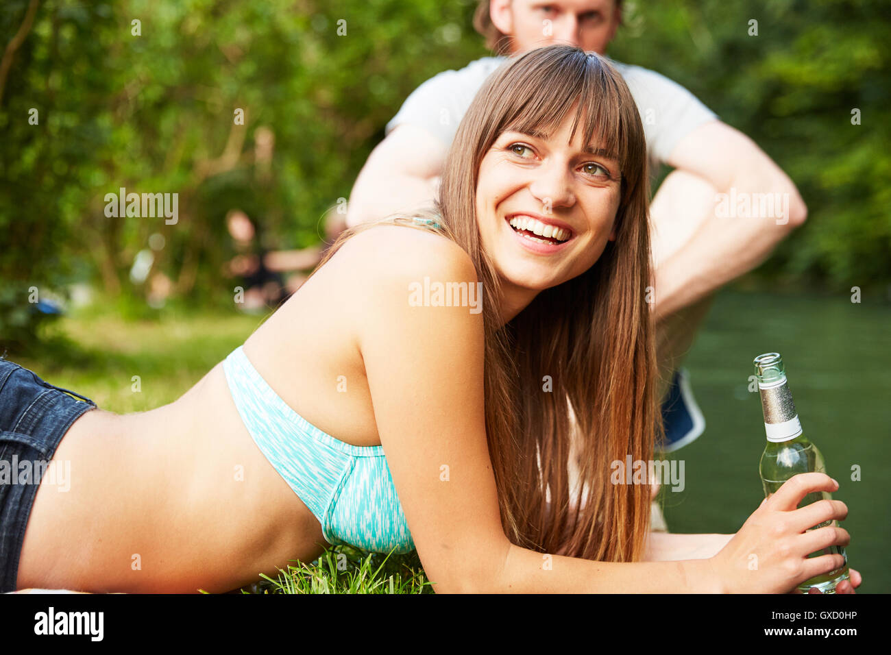 Couple relaxing in park, young woman holding glass bottle Stock Photo