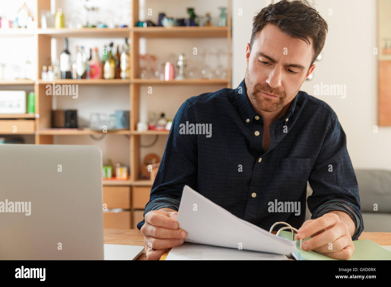 Man with laptop looking at paperwork Stock Photo