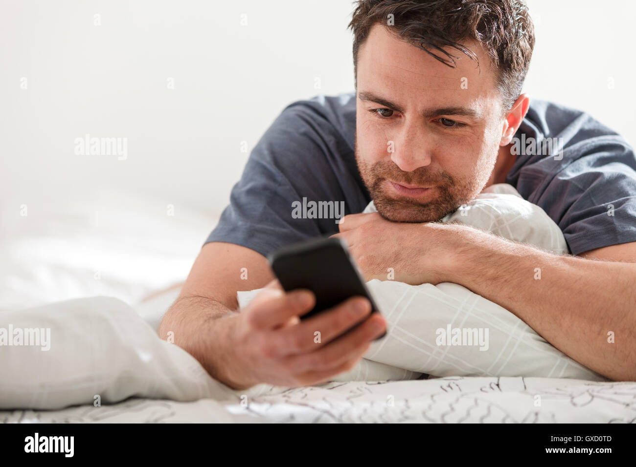 Man lying down using smartphone Stock Photo