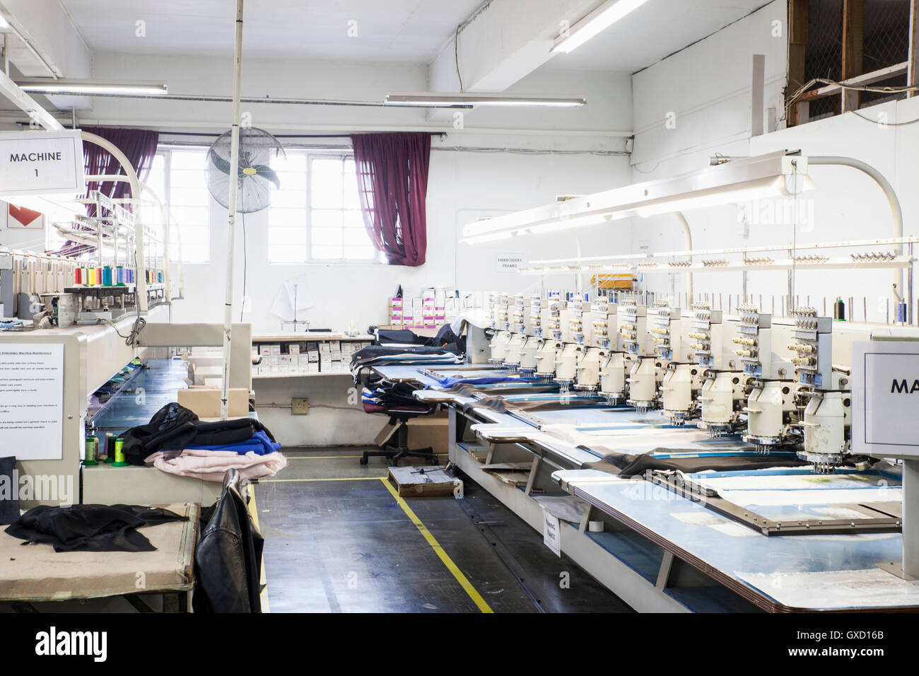 Rows of programmed embroidery machines speed stitching  cloth in clothing factory Stock Photo