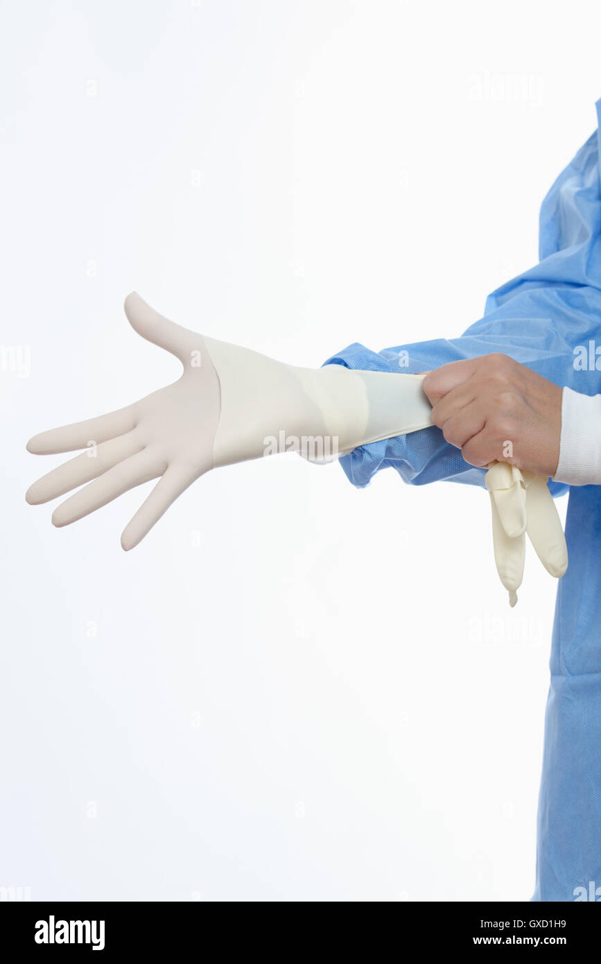 Surgeon putting on latex gloves Stock Photo