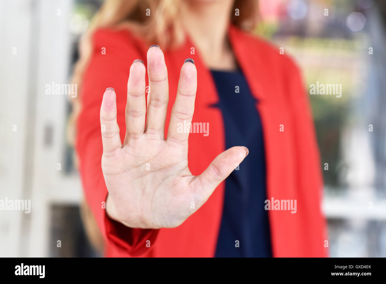 Girl in a red jacket makes stopping gesture open hand - close-up Stock Photo