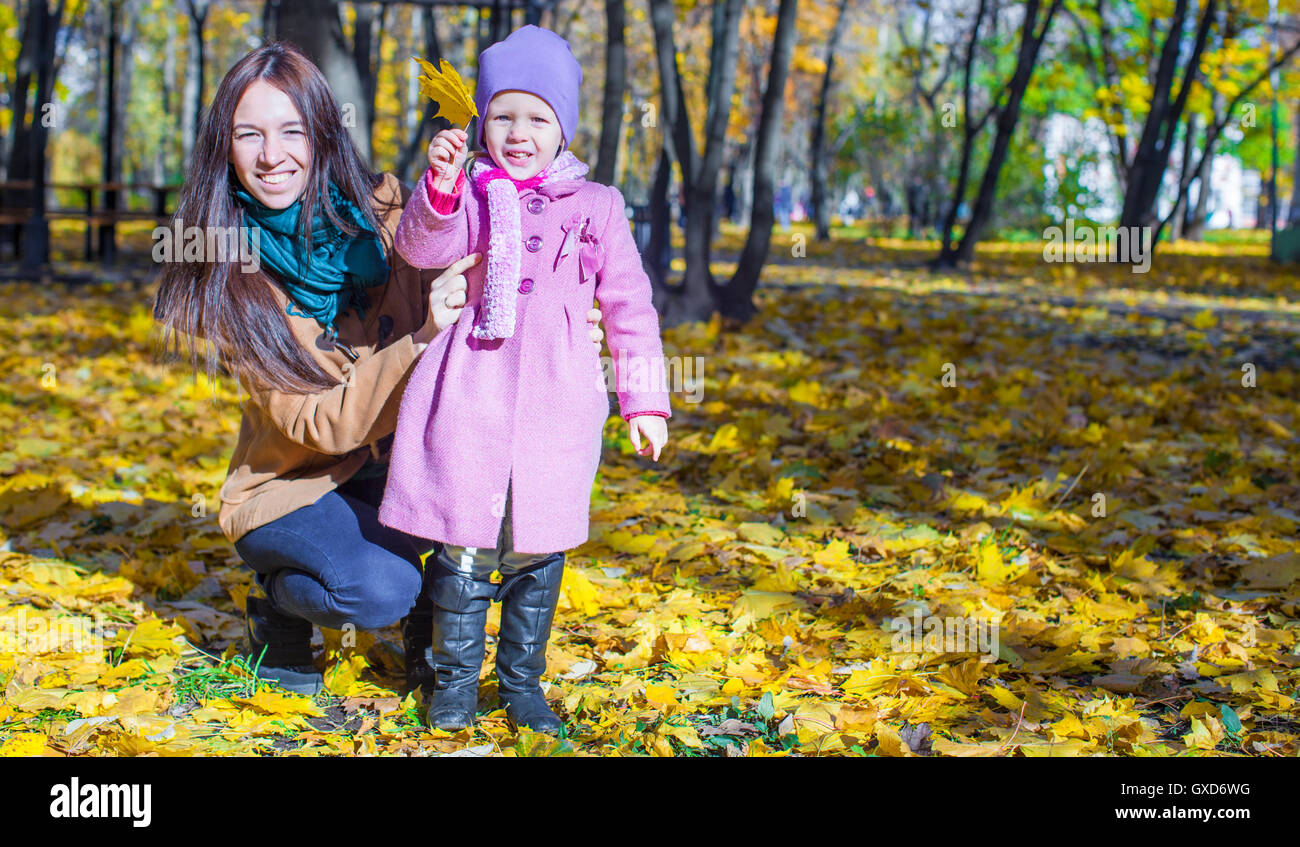 Little girl with young mother in yellow autumn park on a warm sunny day ...