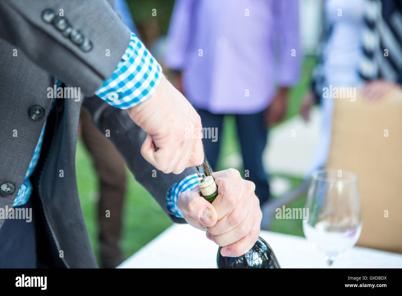 Male hands uncorking wine bottle at garden party table Stock Photo