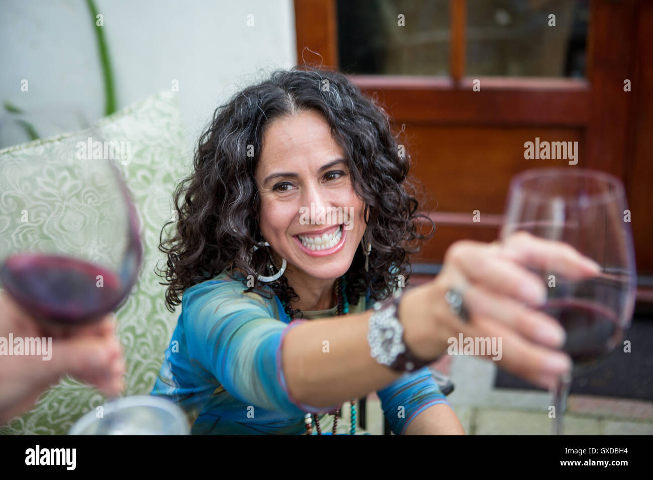Over shoulder view of mature women making red wine toast at garden party Stock Photo