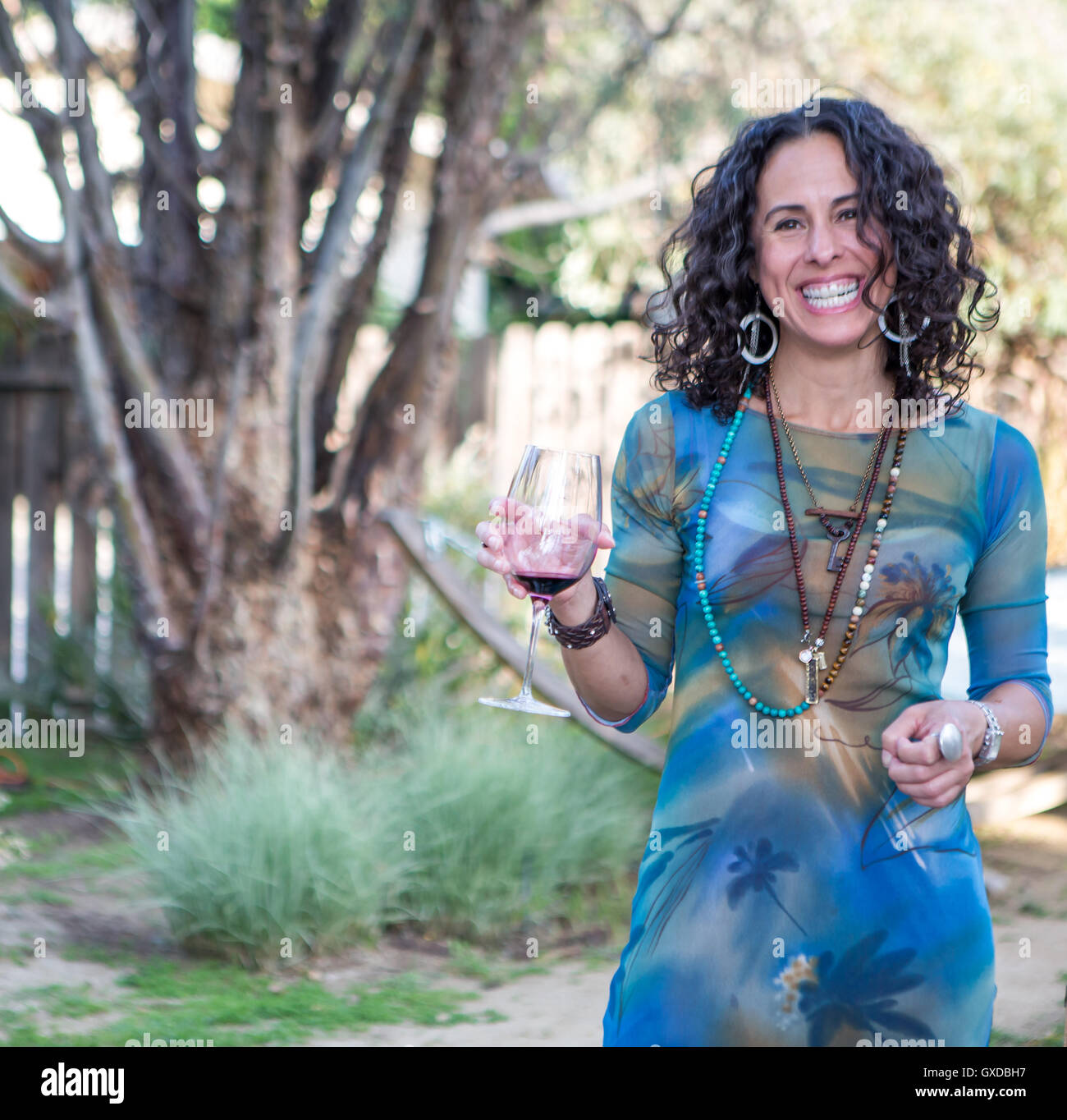 Portrait of mature woman holding red wine at garden party Stock Photo