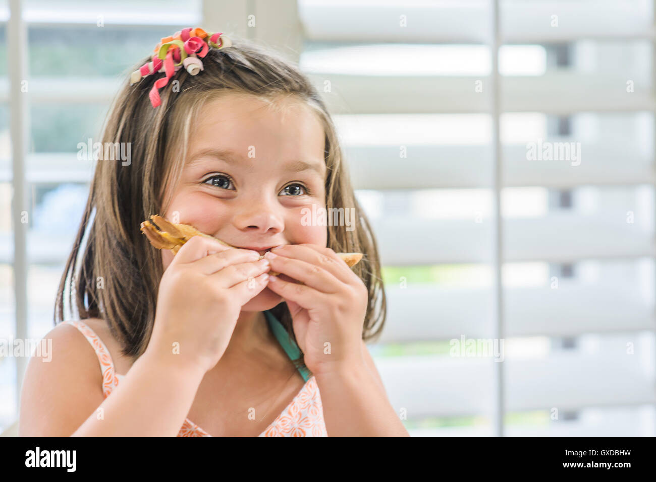 Cute girl eating sandwich in kitchen Stock Photo