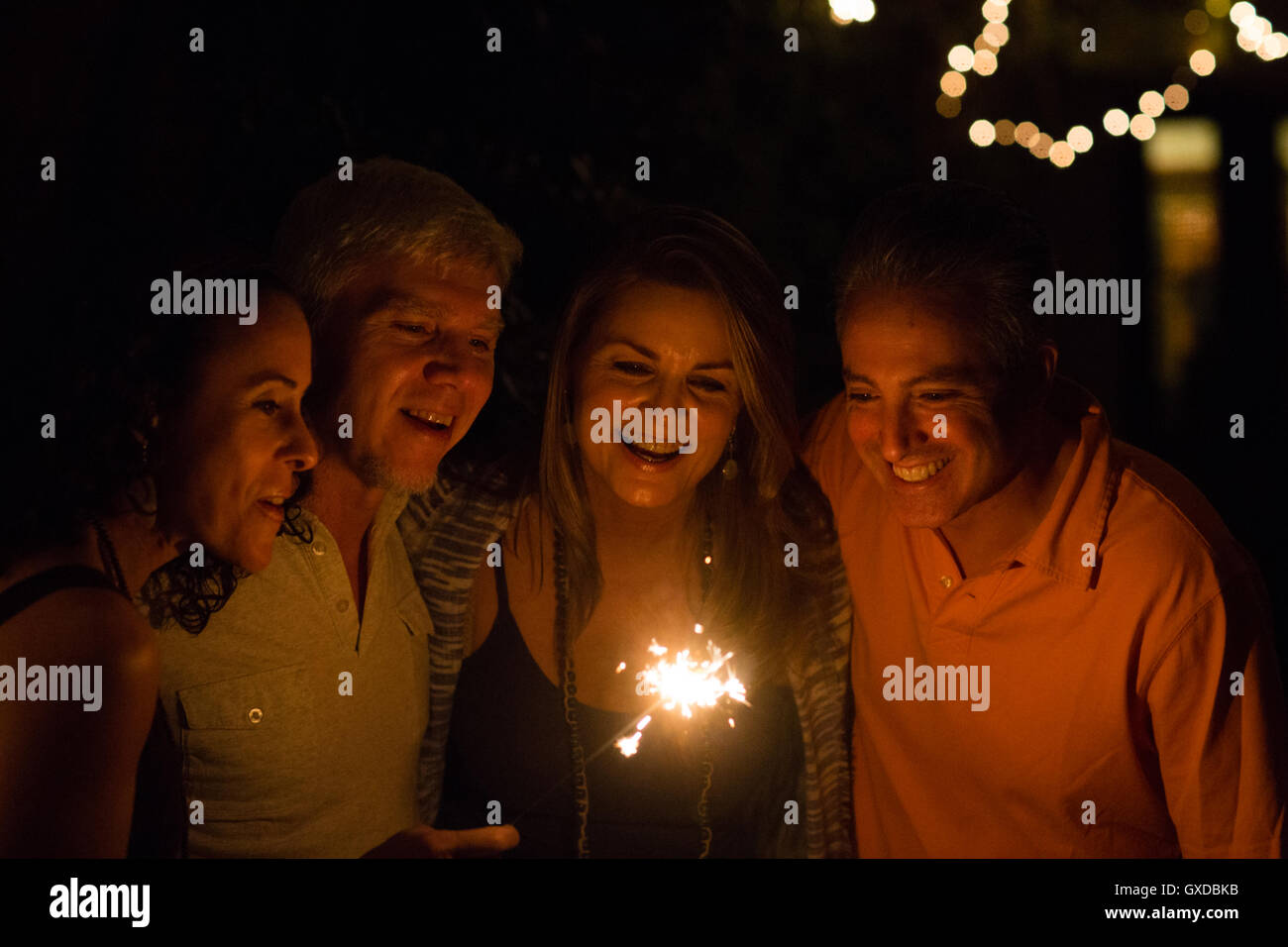 Mature adult couples playing with sparkler in garden at night Stock Photo