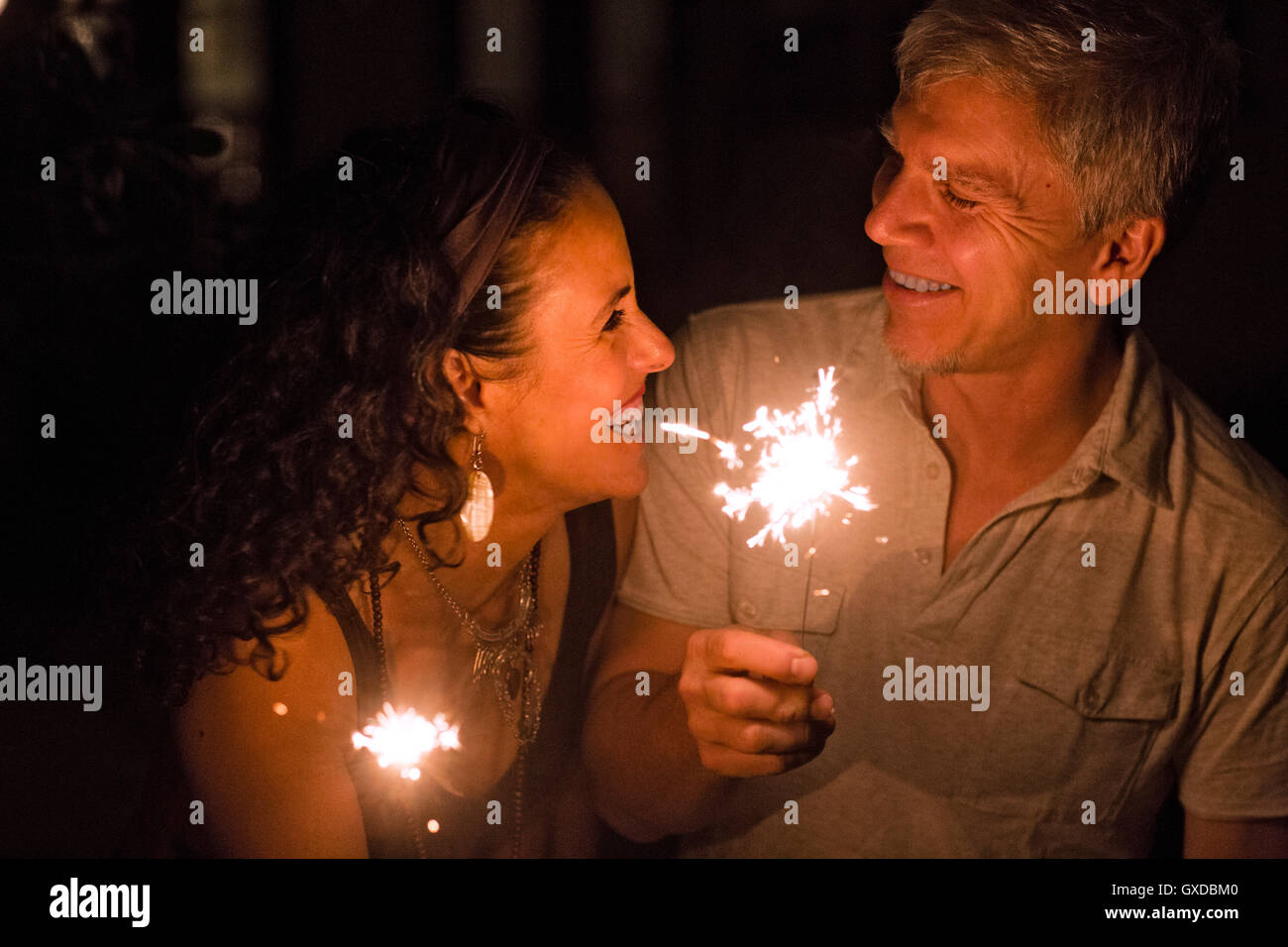 Happy romantic mature couple holding sparklers at night Stock Photo
