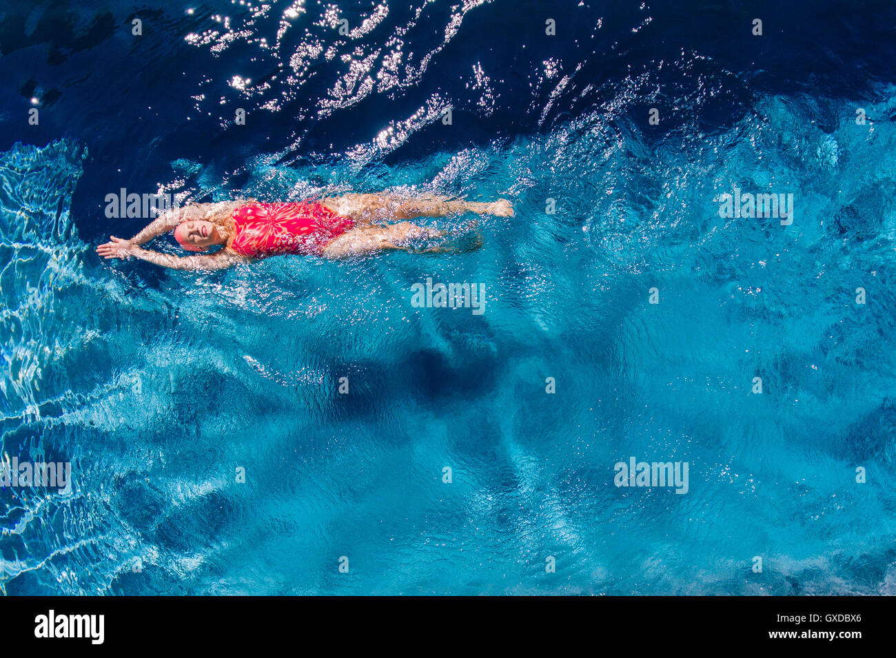 Overhead view of woman swimming on back in swimming pool Stock Photo