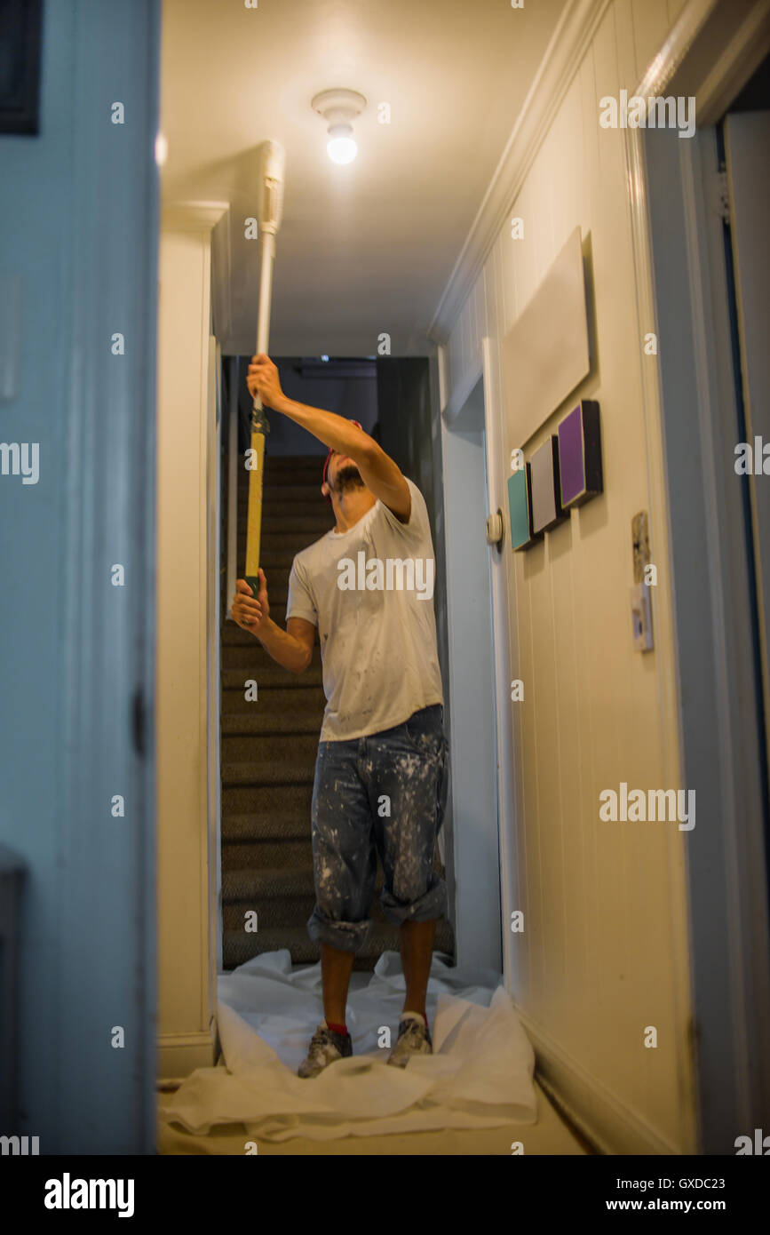 Man Painting Passage Ceiling With Paint Roller Stock Photo