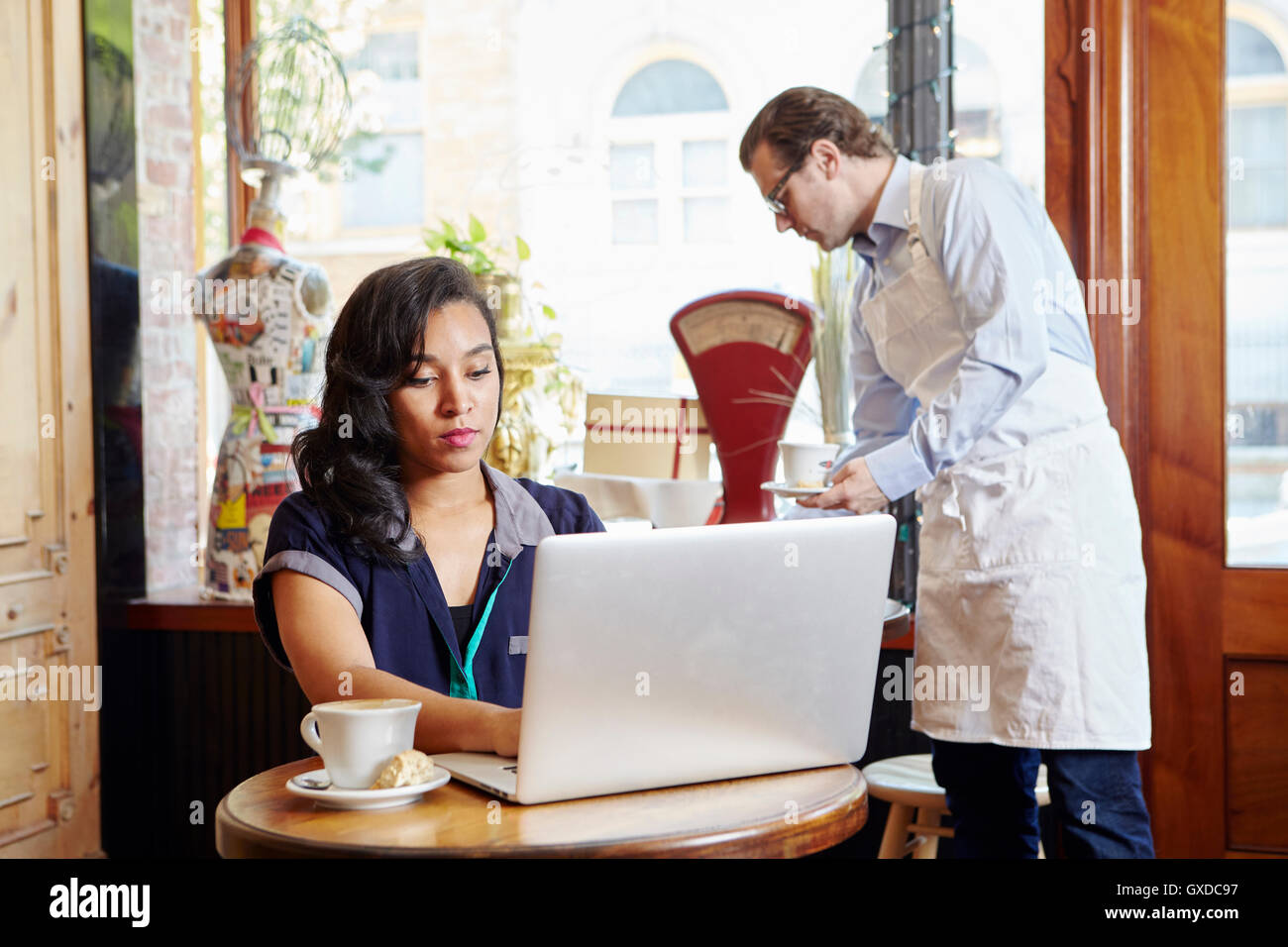 Young woman sitting in cafe, using laptop Stock Photo