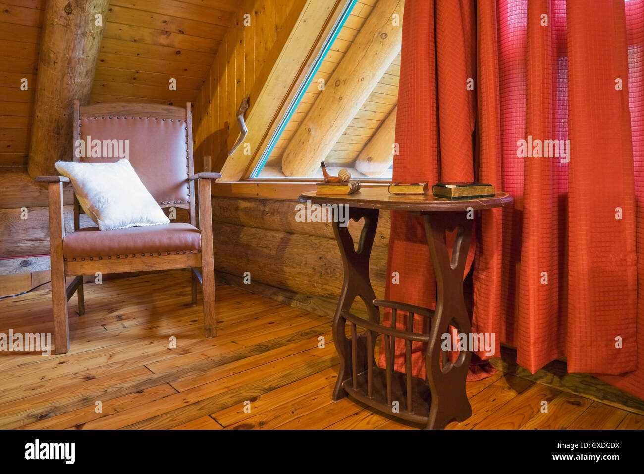 Brown wooden leather chair and side table in master bedroom in Scandinavian cottage-style log home, Quebec, Canada Stock Photo