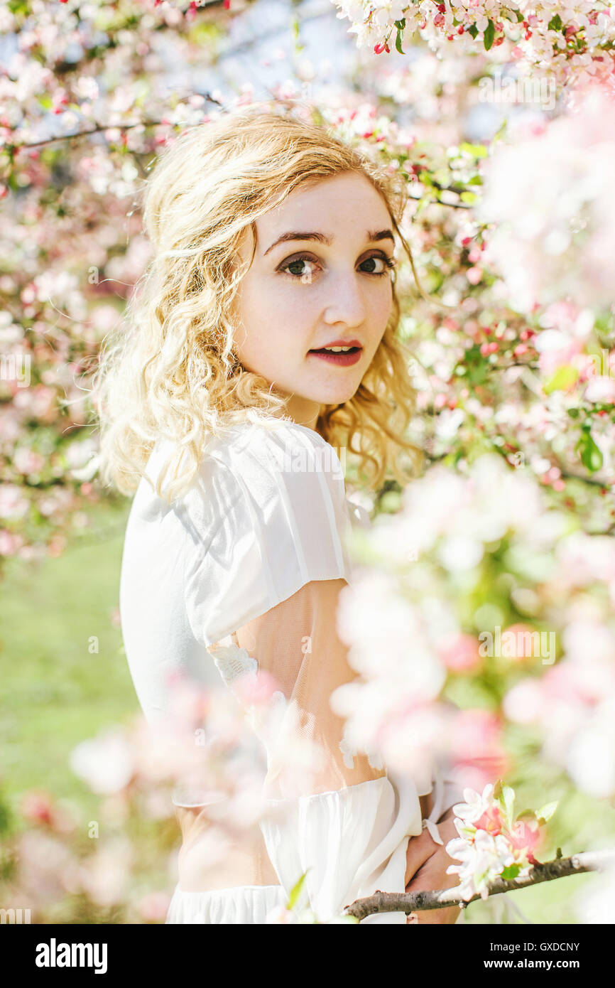 Portrait of woman by cherry blossom tree looking at camera Stock Photo