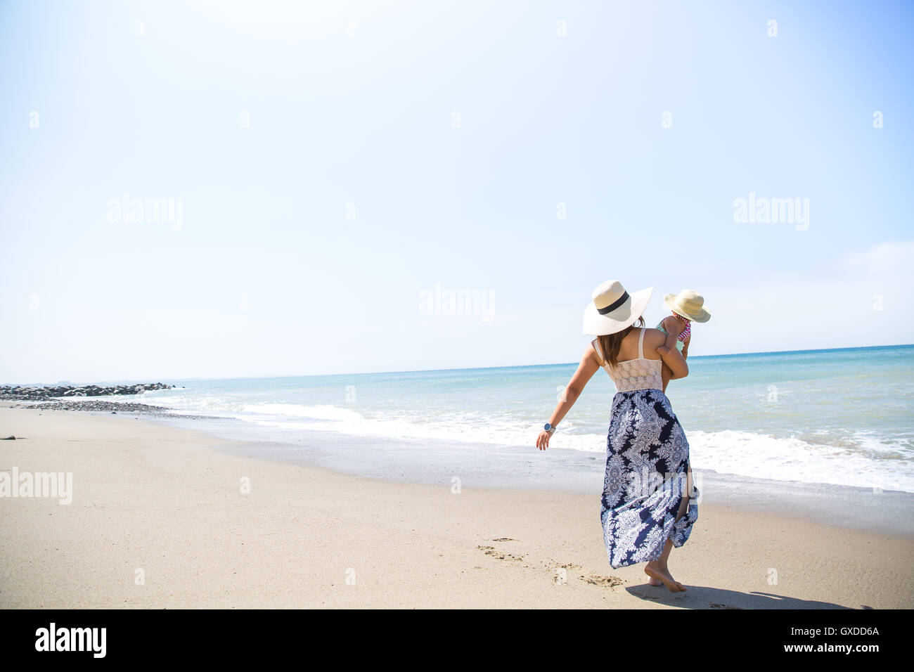 Rear view of mother carrying baby son on beach, Malibu, California, USA Stock Photo