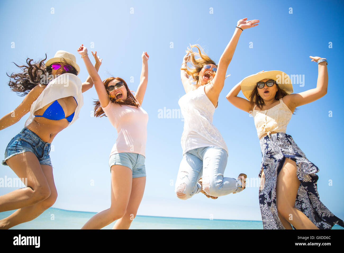Four adult female friends jumping mid air on beach, Malibu, California, USA Stock Photo