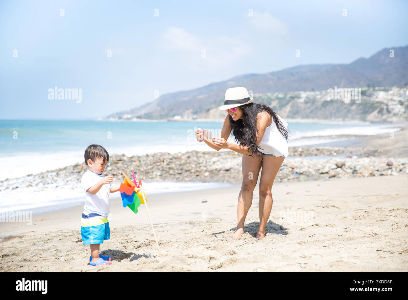 Mother photographing baby son on beach, Malibu, California, USA Stock Photo