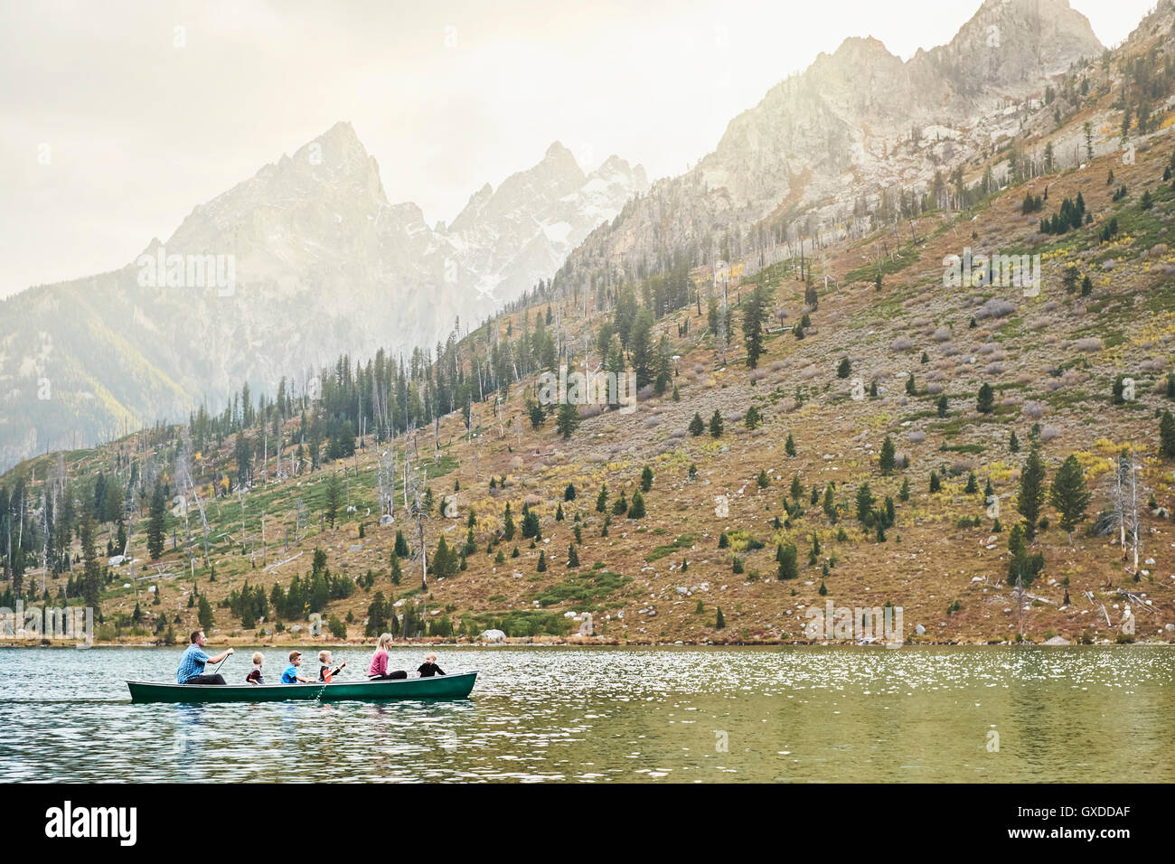 Family with four children paddling canoe on lake, Grand Teton National