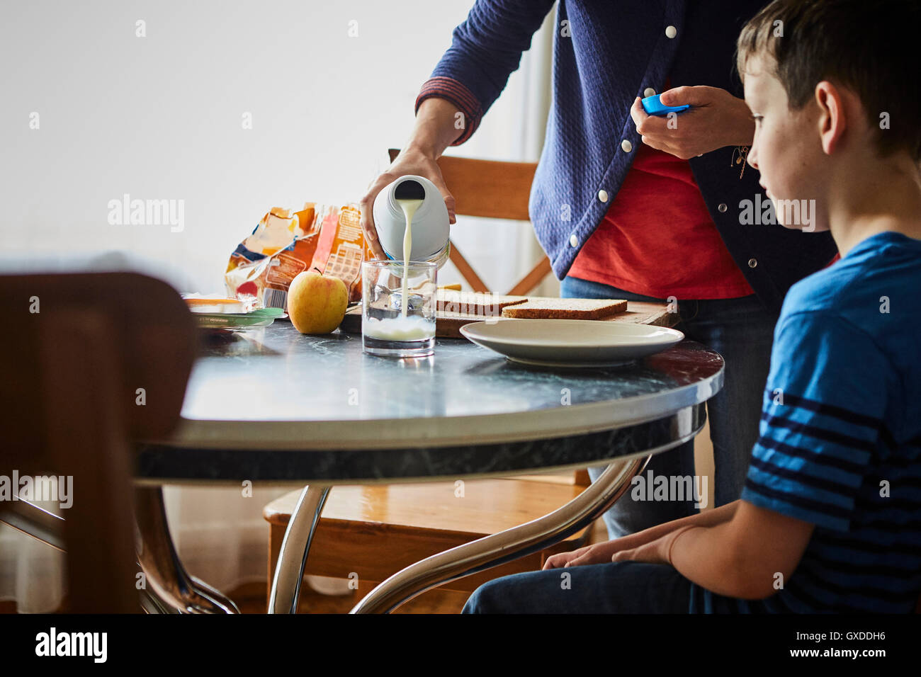 Mother pouring glass of milk for son Stock Photo