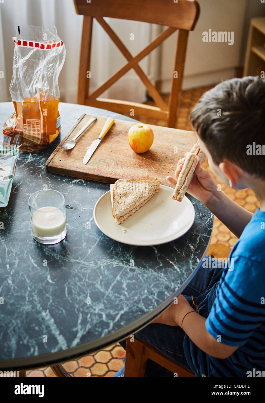 Boy at dining table eating sandwich Stock Photo