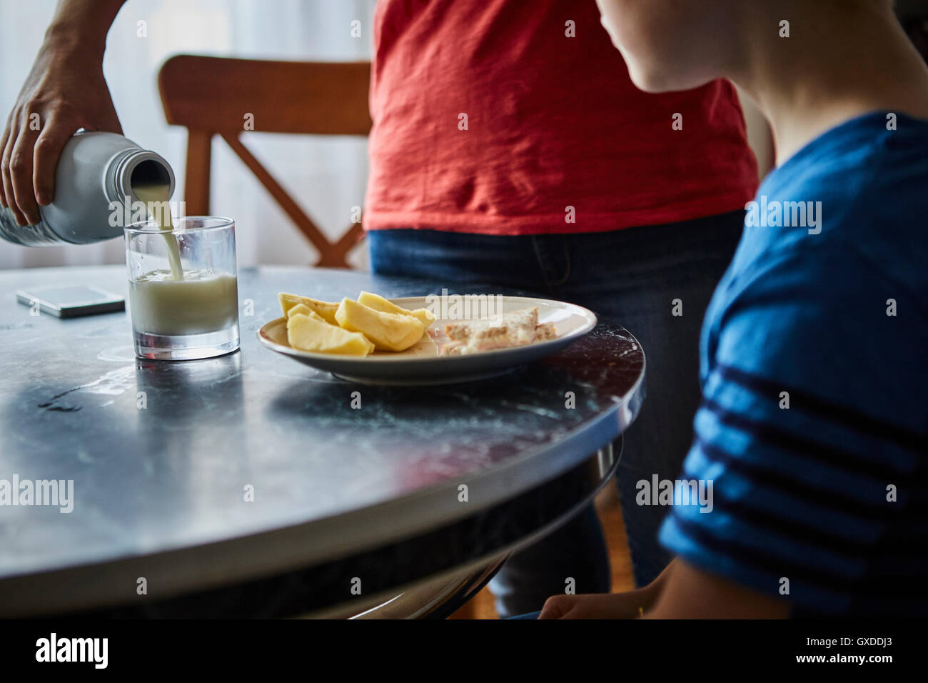 Mother pouring milk for son Stock Photo