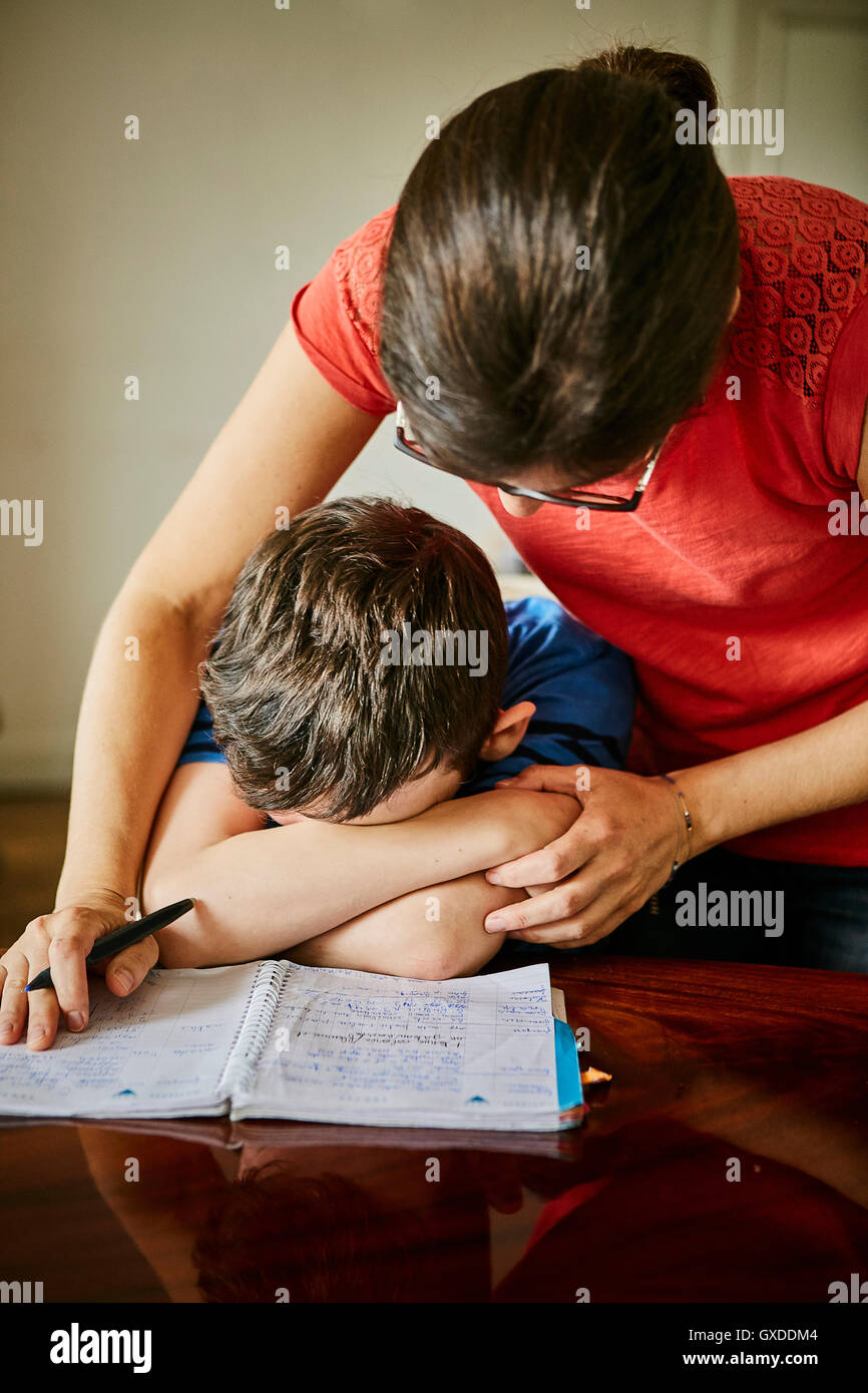 Mother comforting upset son doing homework Stock Photo