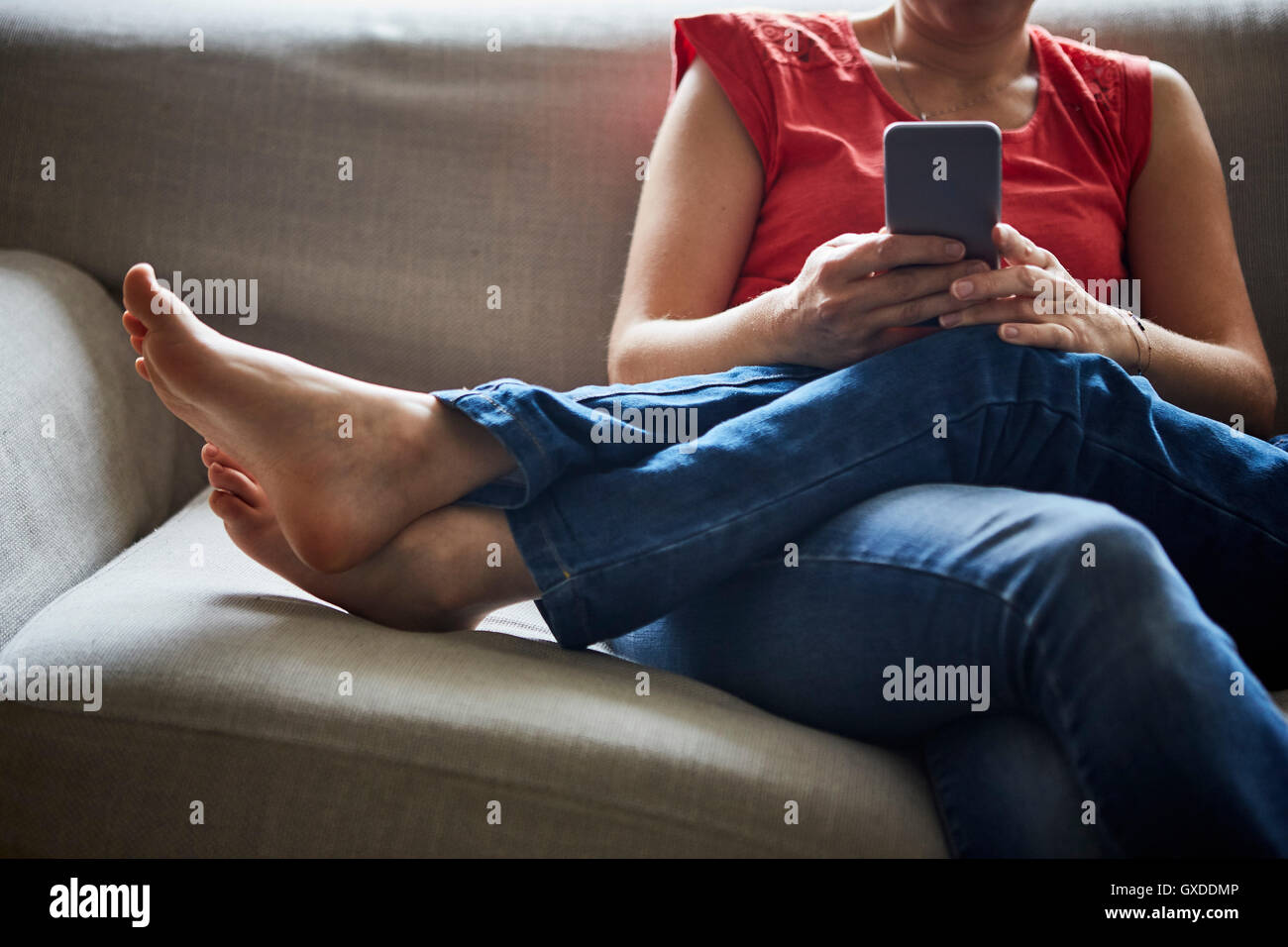 Cropped view of mother and son relaxing on sofa using smartphone Stock Photo