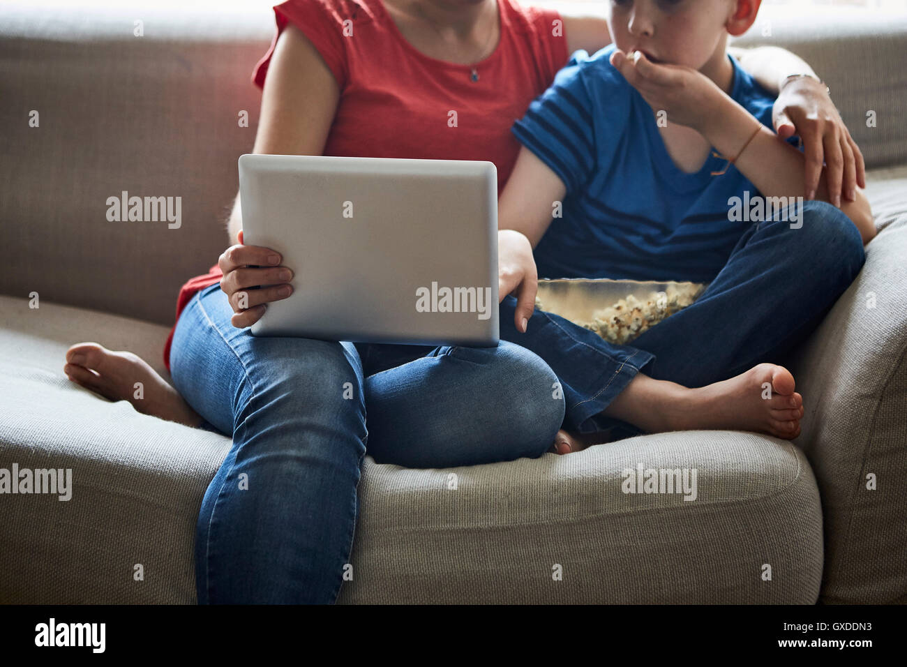 Cropped view of mother and son on sofa with popcorn using smartphone Stock Photo