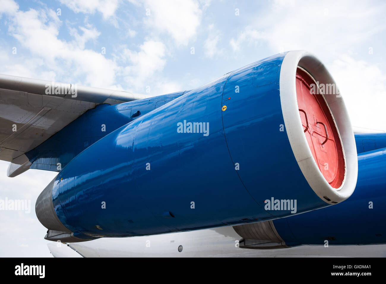 Blue side engine nacelle of a modern turbo-jet heavy aircraft. Pale blue sky and white clouds in the background Stock Photo