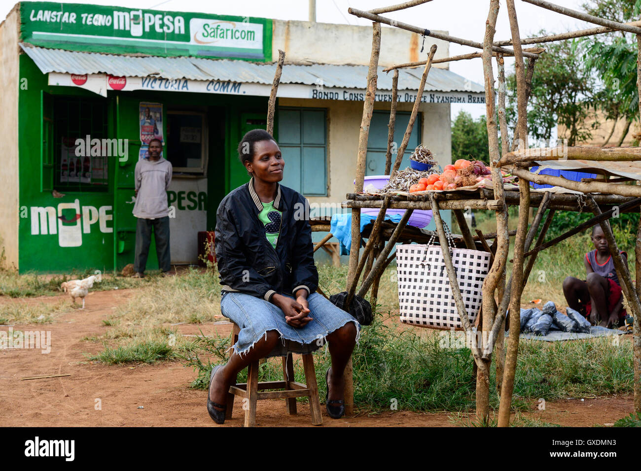 KENIA, County Siaya, village Kotanega, shop M-Pesa, of company Safari.com a joint venture of Vodafone and kenyan telephone, payment by mobile phone, market woman sells vegetables / KENIA, bezahlen per Mobiltelefon, M-Pesa von Safari.com a joint venture von Vodafone and kenyan telephone, Marktfrau verkauft Gemuese Stock Photo