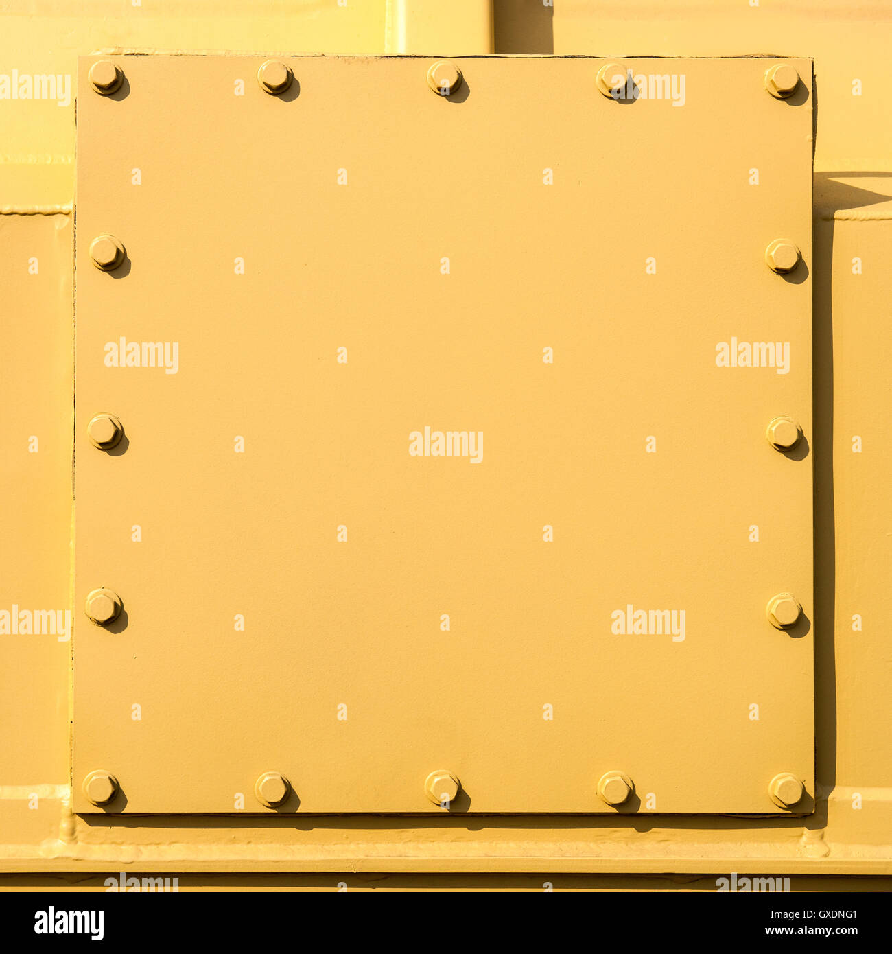 Welded and bolted metal plates painted with yellow colors. Closeup view. Free square shape space to enter a text. Stock Photo