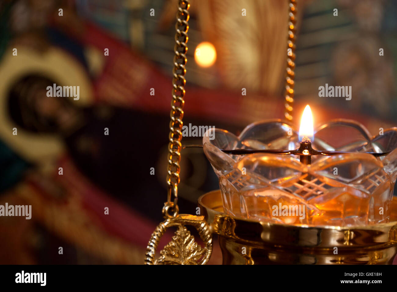 Russian orthodox church interior detail: alight icon lamp with blurred icons as a background. Stock Photo