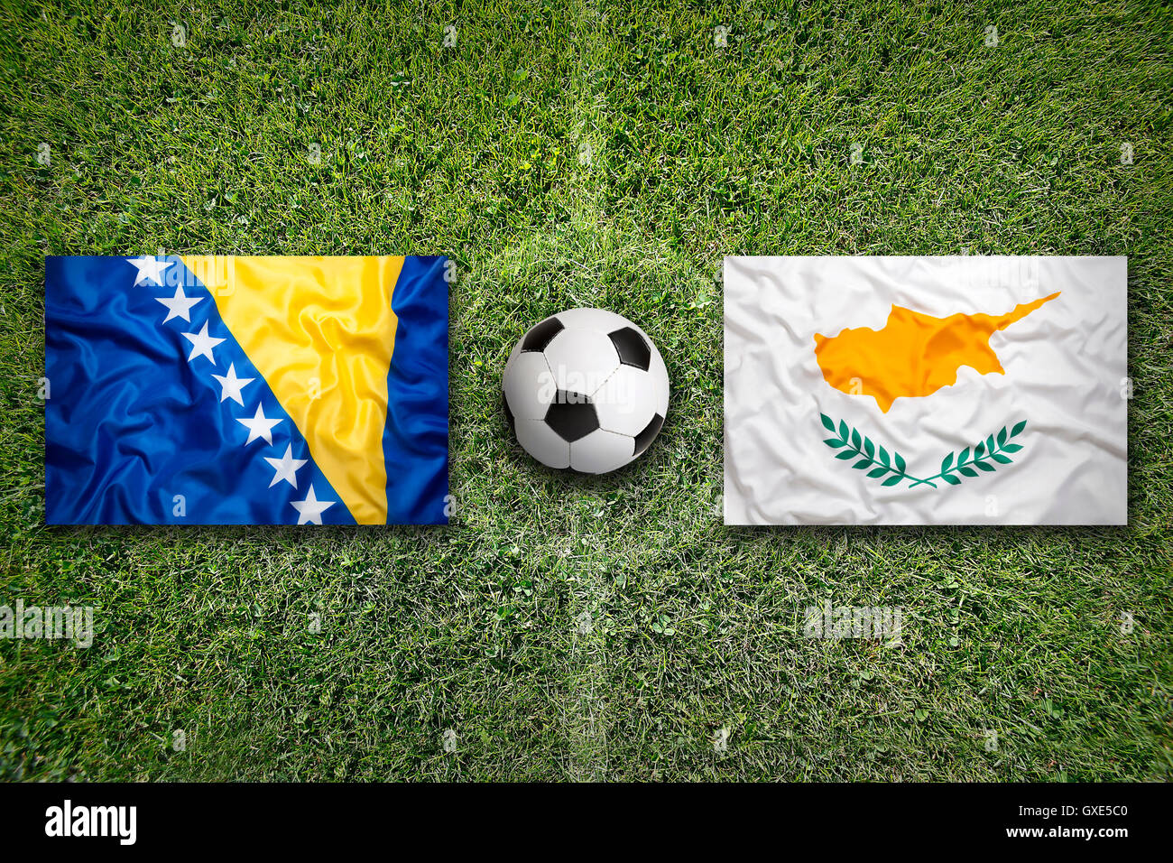 Bosnia and Herzegovina and Cyprus flags on a green soccer field Stock Photo