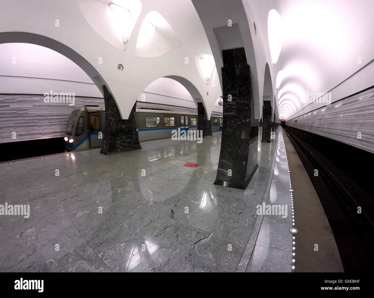 An interior of a subway station in Moscow (Russia) with a train that arrives to the platform. Shot with fish-eye lens. Stock Photo