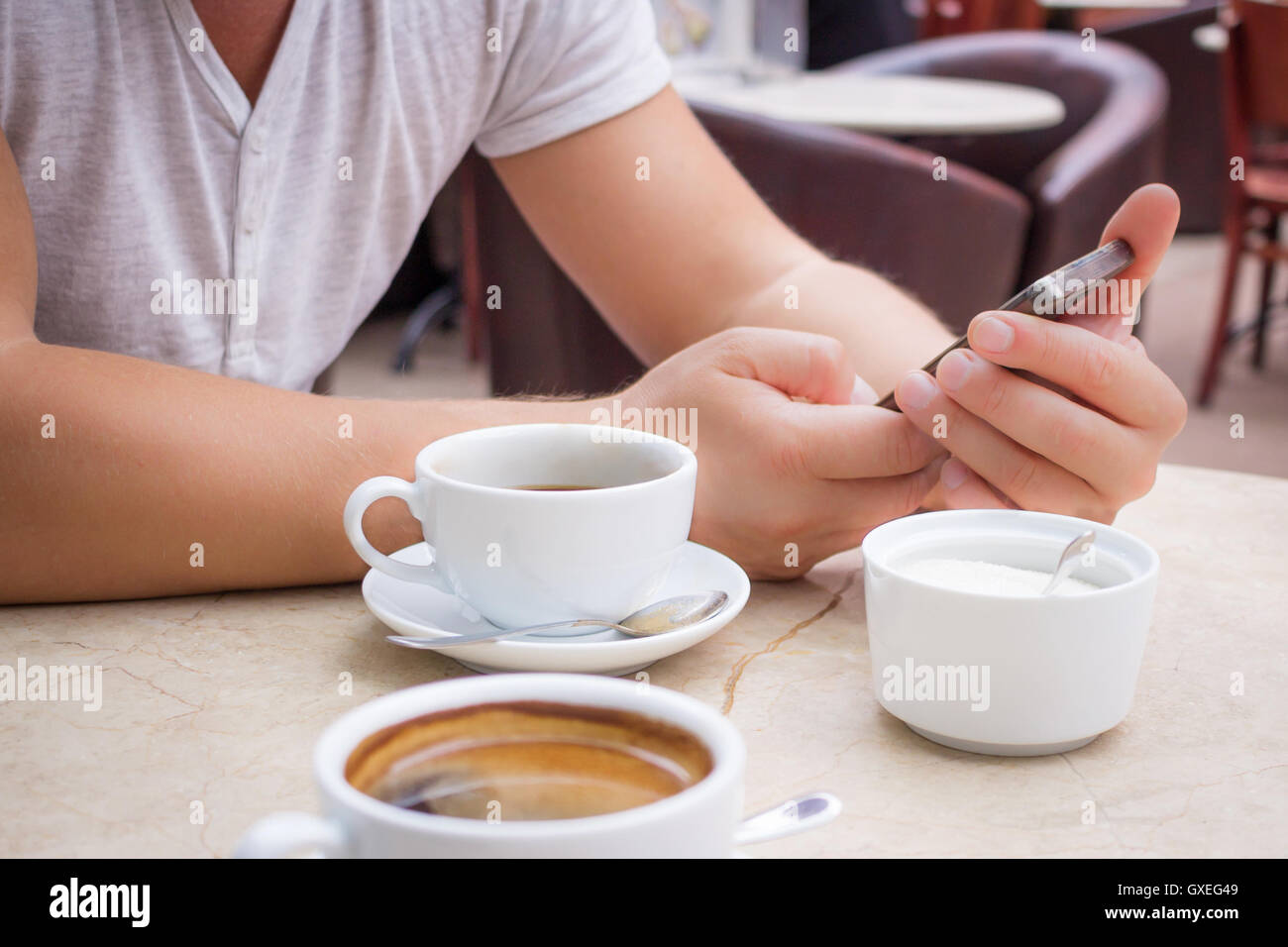 Man sits with smartphone at marble table with cup of coffee Stock Photo