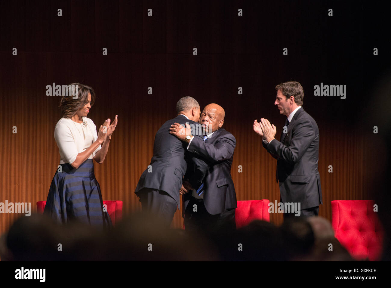 First Lady Michelle Obama and library director Mark Updegrove look on as U.S. President Barack Obama hugs civil rights leader Rep. John Lewis during a program at the LBJ Presidential Library April 10, 2014 in Austin, Texas Stock Photo