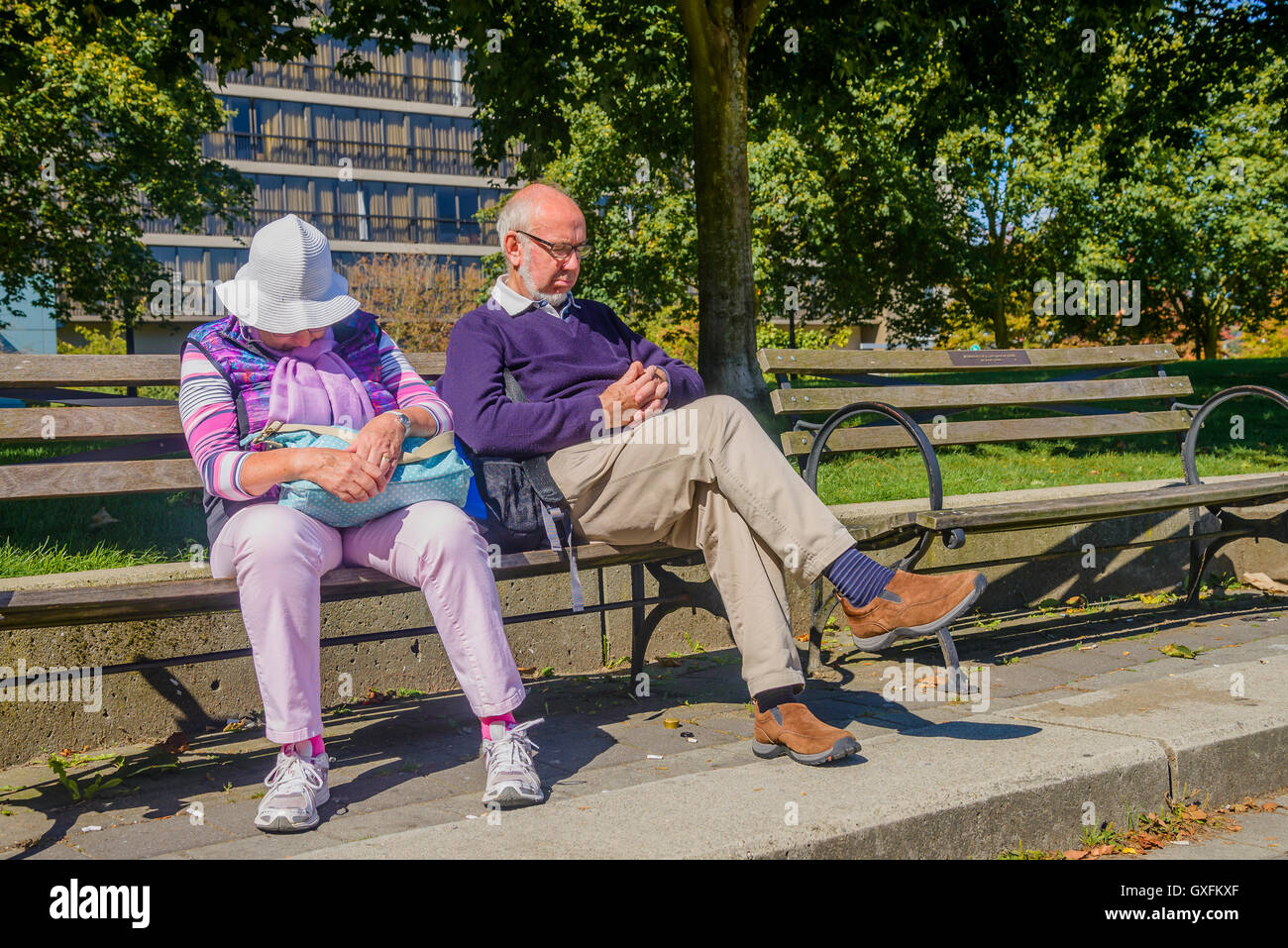 Elderly couple asleep on park bench Stock Photo