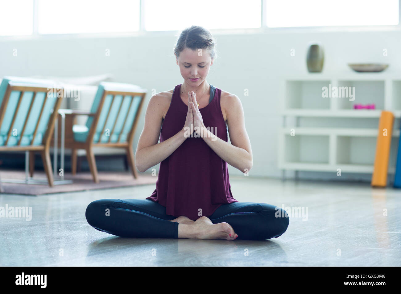 Caucasian woman sitting on floor meditating Stock Photo - Alamy