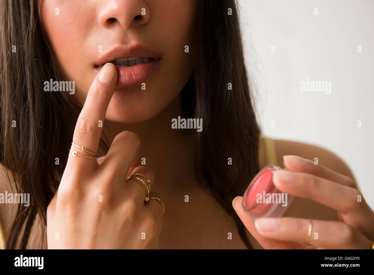 Hispanic woman applying lip gloss Stock Photo