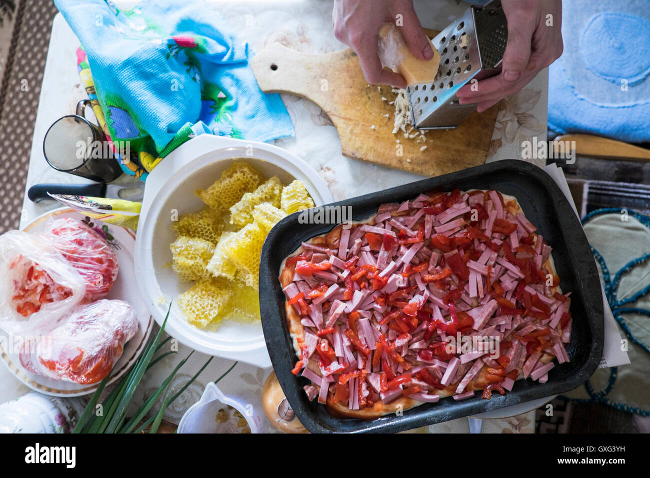 Hand grating cheese onto cutting board for pizza Stock Photo