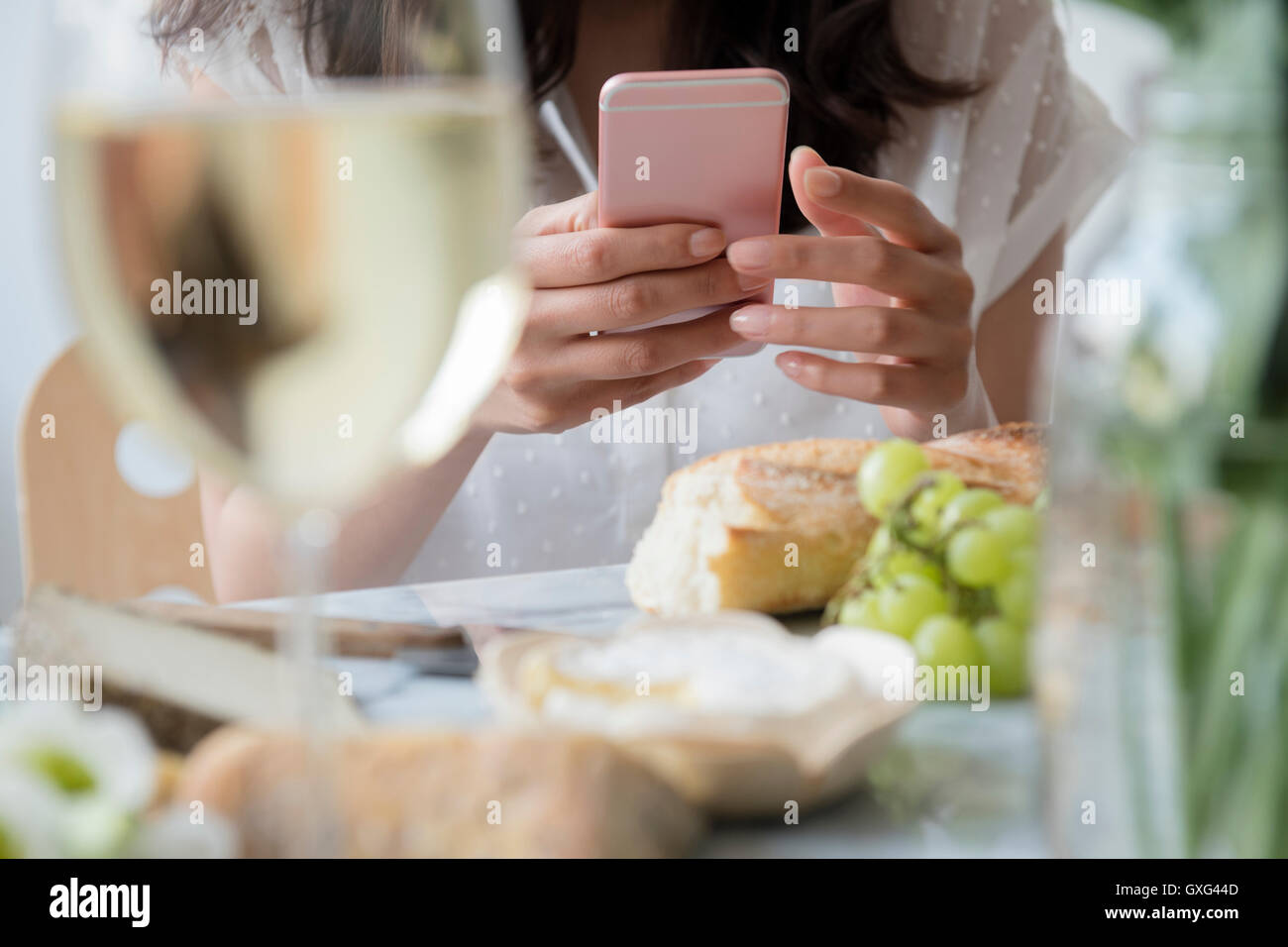 Hispanic woman texting on cell phone at table Stock Photo - Alamy